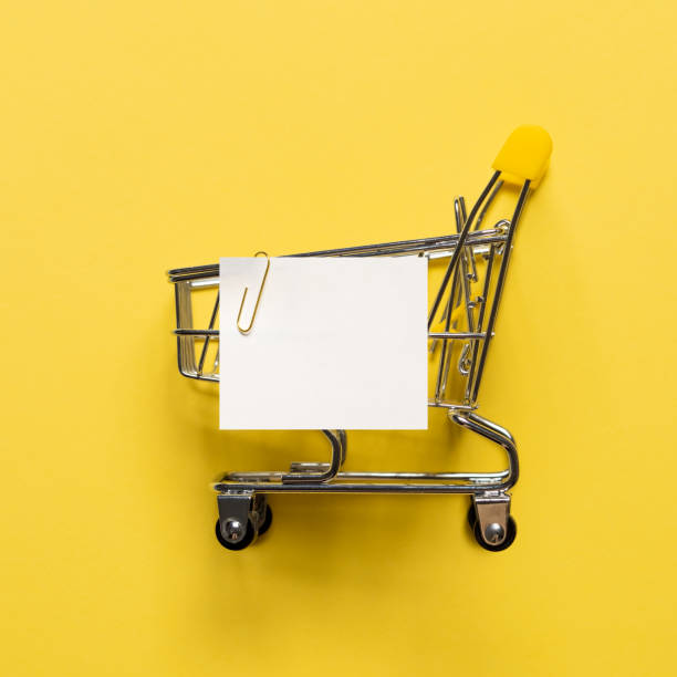 istock Shopping cart and white paper note list on yellow 1158376265