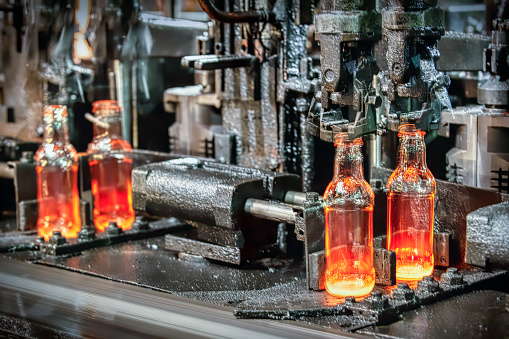 Hot glass comes out of molds in glass bottle manufacturing