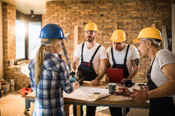istock Female building contractor giving instructions to group of workers on construction site. 1158380187