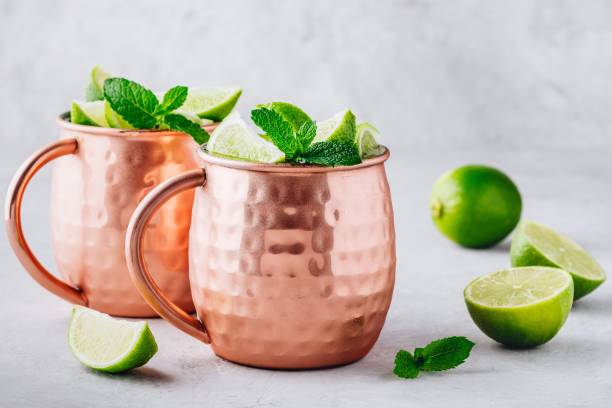 istock Moscow mule ice cold cocktail in copper cup with lime and and mint on gray stone background 1158381559
