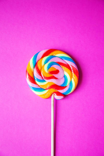 istock Colorful rainbow lollipop, pink background, centered, vertical 1158381667