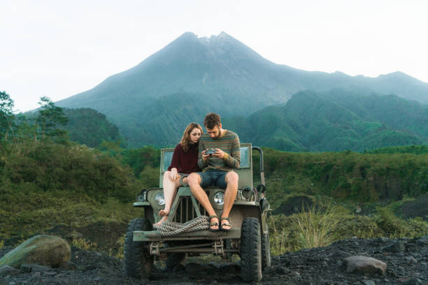 메라피 화산을 배경으로 구식 suv에 앉아 있는 커플의 경치 - mt merapi 뉴스 사진 이미지