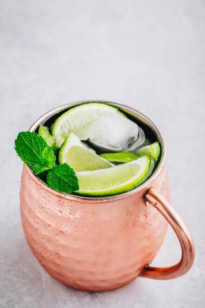 istock Moscow mule ice cold cocktail in copper cup with lime and and mint on gray stone background 1158381796