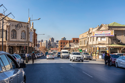 Fordsburg street view towards Johannesburg city with pedestrians and traffic with the old edwardian buildings in disrepair.\nFordsburg is an old historical area where mainly indian, turkish, pakistani and other east asian cultures coexist with restaurants and spice dealers.
