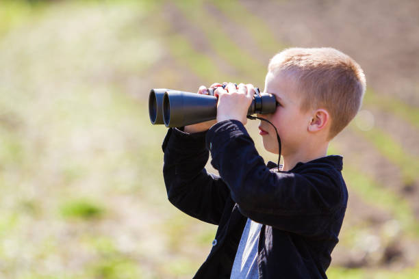 istock Portrait in profile of little handsome cute blond boy looking thoughtfully through binoculars in distance on blurred background. Children dreams, fantasies and imaginations concept. 1158386889