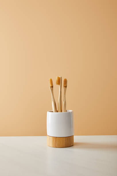 bamboo toothbrushes in holder on white table and beige background