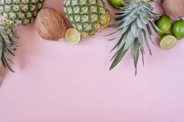 istock Summer composition. Tropical fruits - pineapple, coconut, lime on pastel pink background. Summer concept. Flat lay, top view, copy space 1158390300