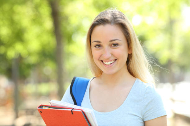 istock Happy teenage student looking at camera in a park 1158391104