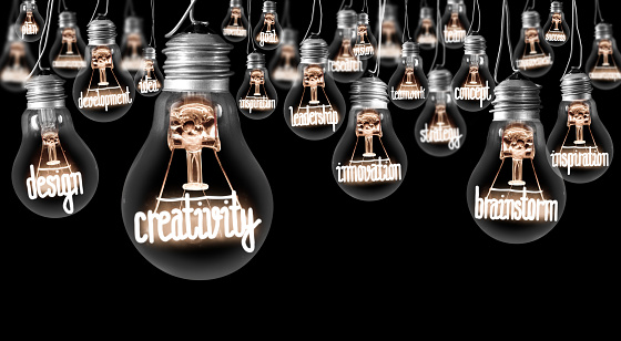 Photo of light bulbs with shining fibers in a shape of Creativity, Brainstorm and Innovation concept related words isolated on black background