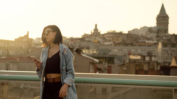 woman using phone in front of galata tower