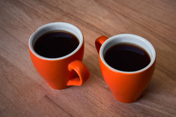 istock pair of orange coffee cups on wooden surface 1158393237