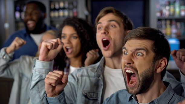 istock Cheering group of sport fans rejoicing team victory, watching match together 1158394251