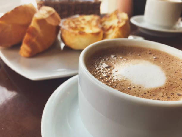 브라질 식 아침 식사.  카푸치노 컵과 버터 배경의 구운 빵. - cappuccino coffee breakfast freshness 뉴스 사진 이미지
