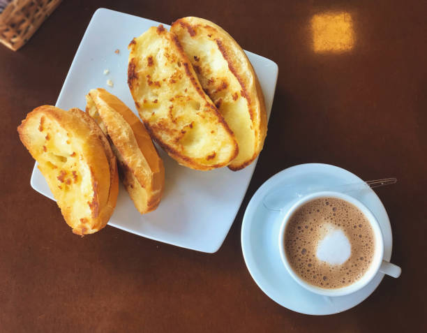 브라질 식 아침 식사.  카푸치노 컵과 버터 배경의 구운 빵. - cappuccino coffee breakfast freshness 뉴스 사진 이미지