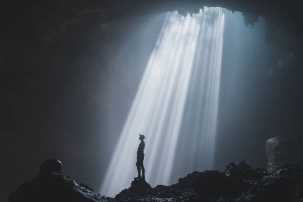 istock Man standing in Jomblan Cave in sunbeams 1158395744