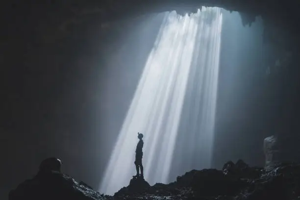 Silhouette of man standing in Jomblan Cave, Java, Indonesia