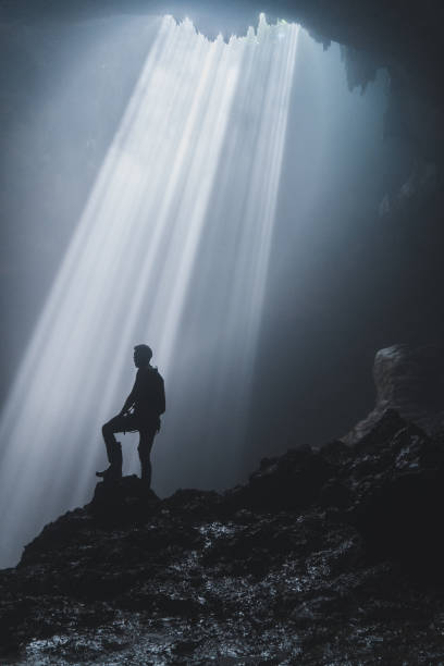 istock Man standing in Jomblan Cave in sunbeams 1158395782
