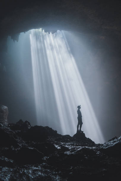 istock Man standing in Jomblan Cave in sunbeams 1158395784