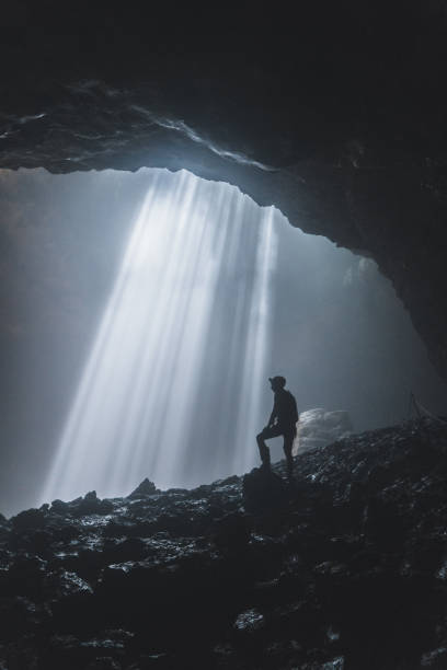 istock Man standing in Jomblan Cave in sunbeams 1158395843