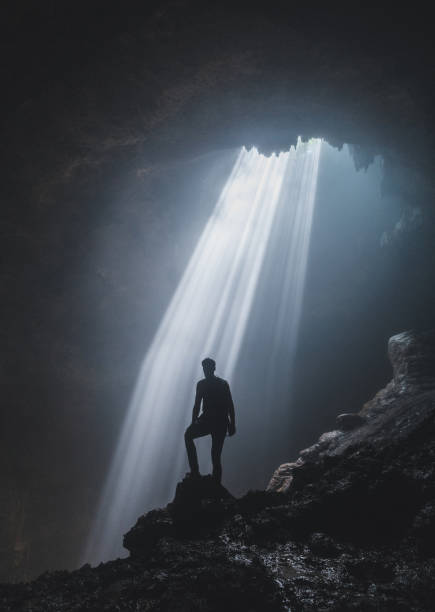 istock Man standing in Jomblan Cave in sunbeams 1158395846