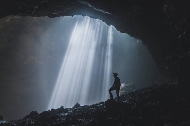 istock Man standing in Jomblan Cave in sunbeams 1158395863