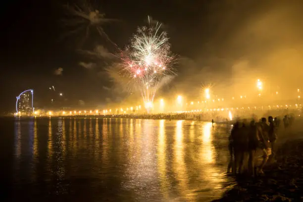 people gather on barceloneta beach in barcelona to party and celebrate traditional san juan holiday with fireworks