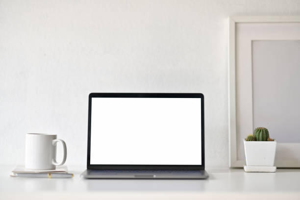 istock Blank white screen laptop with office supplies on white desk workspace. 1158399406