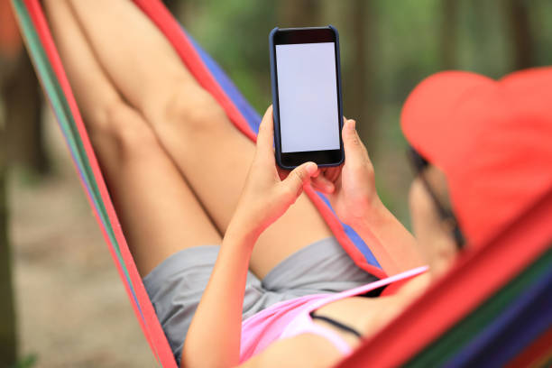 istock Woman hiker relaxing in hammock with smartphone in forest 1158404897