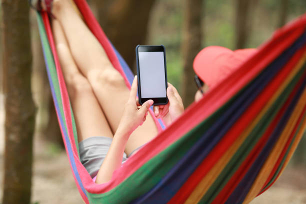 istock Woman hiker relaxing in hammock with smartphone in forest 1158406221