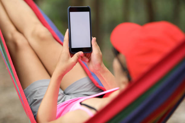 istock Woman hiker relaxing in hammock with smartphone in forest 1158406266