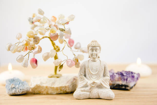 istock Calming meditation background with sitting meditating Buddha, crystal clusters( purple amethyst and blue celestite) and gemstone wire tree white minimalist background with copy space. 1158408490