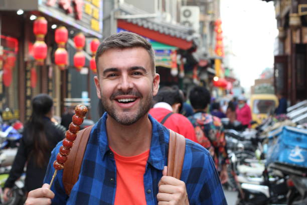スティックでアジアのストリートフードを食べる観光客 - food chinese ethnicity street china ストックフォトと画像
