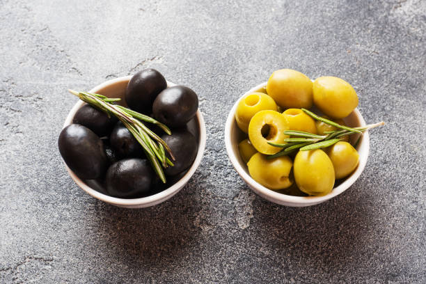 istock Black and green olives in bowls on dark table. Copy space. 1158409817