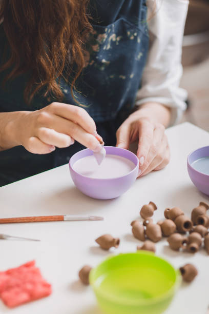 istock Artisan woman glazing a small ceramic pot. 1158410315