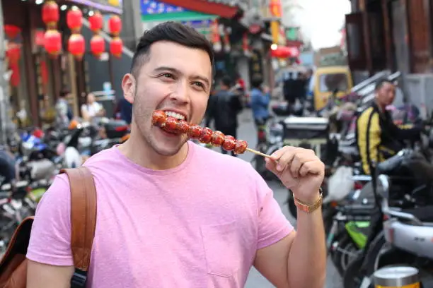 Photo of Man eating sugar-coated haws on a stick in China