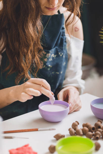 istock Artisan woman glazing a small ceramic pot. 1158410371