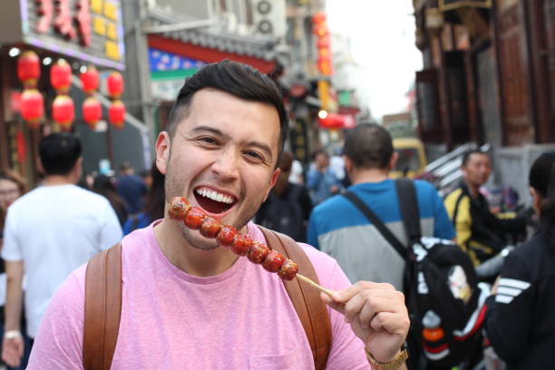 istock Man eating food on a stick in Asia 1158412005