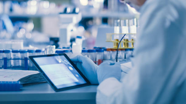 senior male research scientist utilizza un tablet in un moderno laboratorio high-tech. genetica e studi e ricerche farmaceutiche. - research scientist healthcare and medicine discovery foto e immagini stock