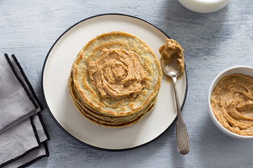 Vegan pancakes with flax seeds, peanut butter and vegan milk on a white plate on a gray background. delicious homemade healthy food