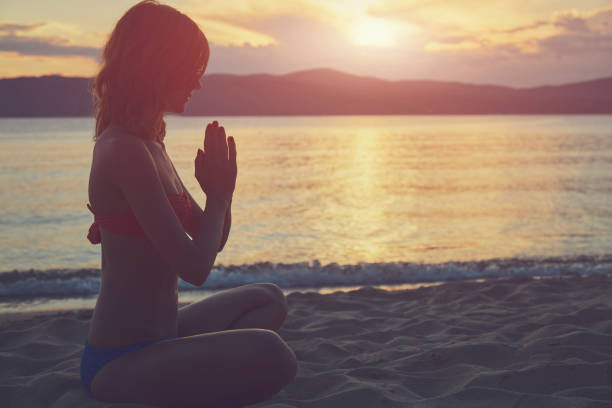 istock Young woman practicing yoga on the sandy beach. 1158424501
