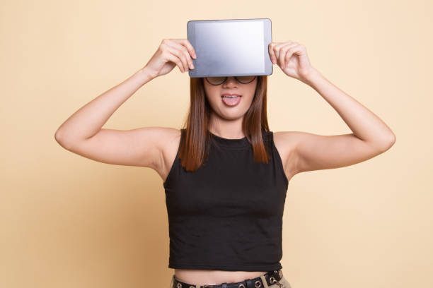 istock Young Asian woman with a computer tablet over her face. 1158424609