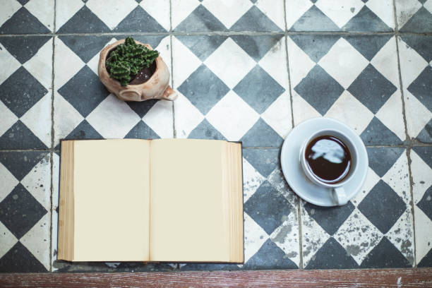 Cup of coffee and book on wooden table, top view