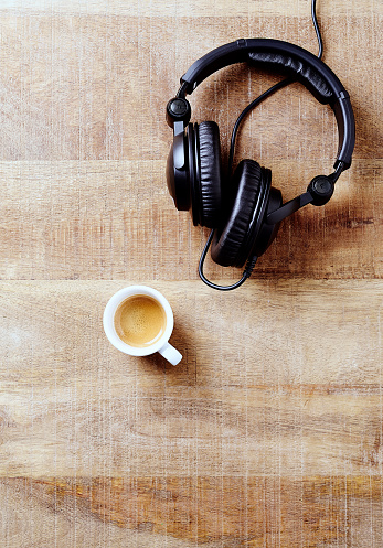 Black headphones and a cup of coffee on rustic wooden background. Directly Above. Copy space.
