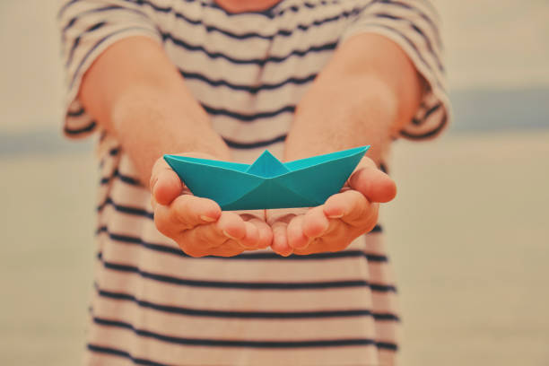 istock Man holding paper boat on tropical beach. 1158425280