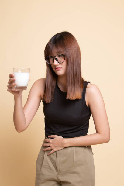 la femme asiatique buvant un verre de lait a eu mal à l'estomac. - got milk photos et images de collection