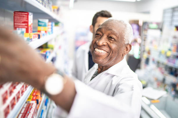 棚の中の薬に手を伸ばす薬剤師 - pharmacy pharmacist smiling pill ストックフォトと画像