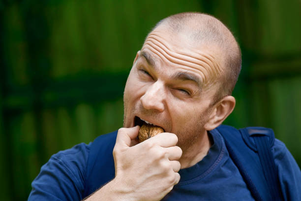 istock man trying to crack a nut with his teeth 1158434065