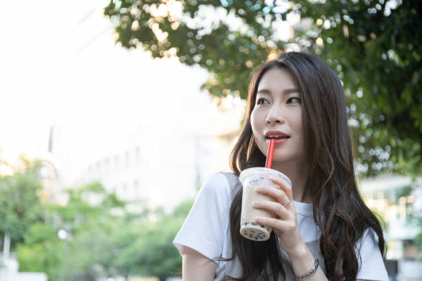 istock Woman drinking tapioca drink in park 1158436469
