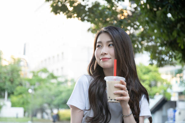 istock Woman drinking tapioca drink in park 1158436484