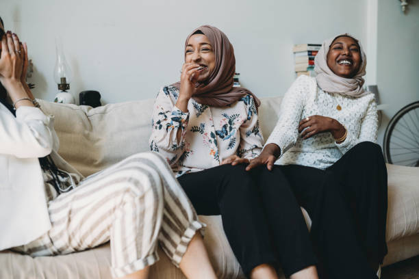 tres amigos hablando juntos sentados en el sofá en casa - islam fotografías e imágenes de stock